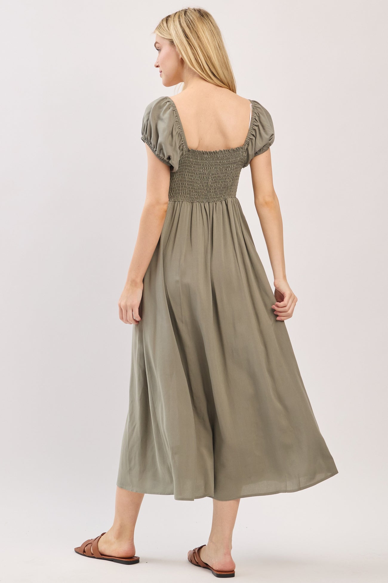 woman wearing a green maxi dress with puff sleeves and a smocked bodice, shown from the back