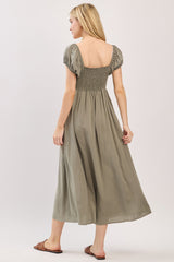 woman wearing a green maxi dress with puff sleeves and a smocked bodice, shown from the back