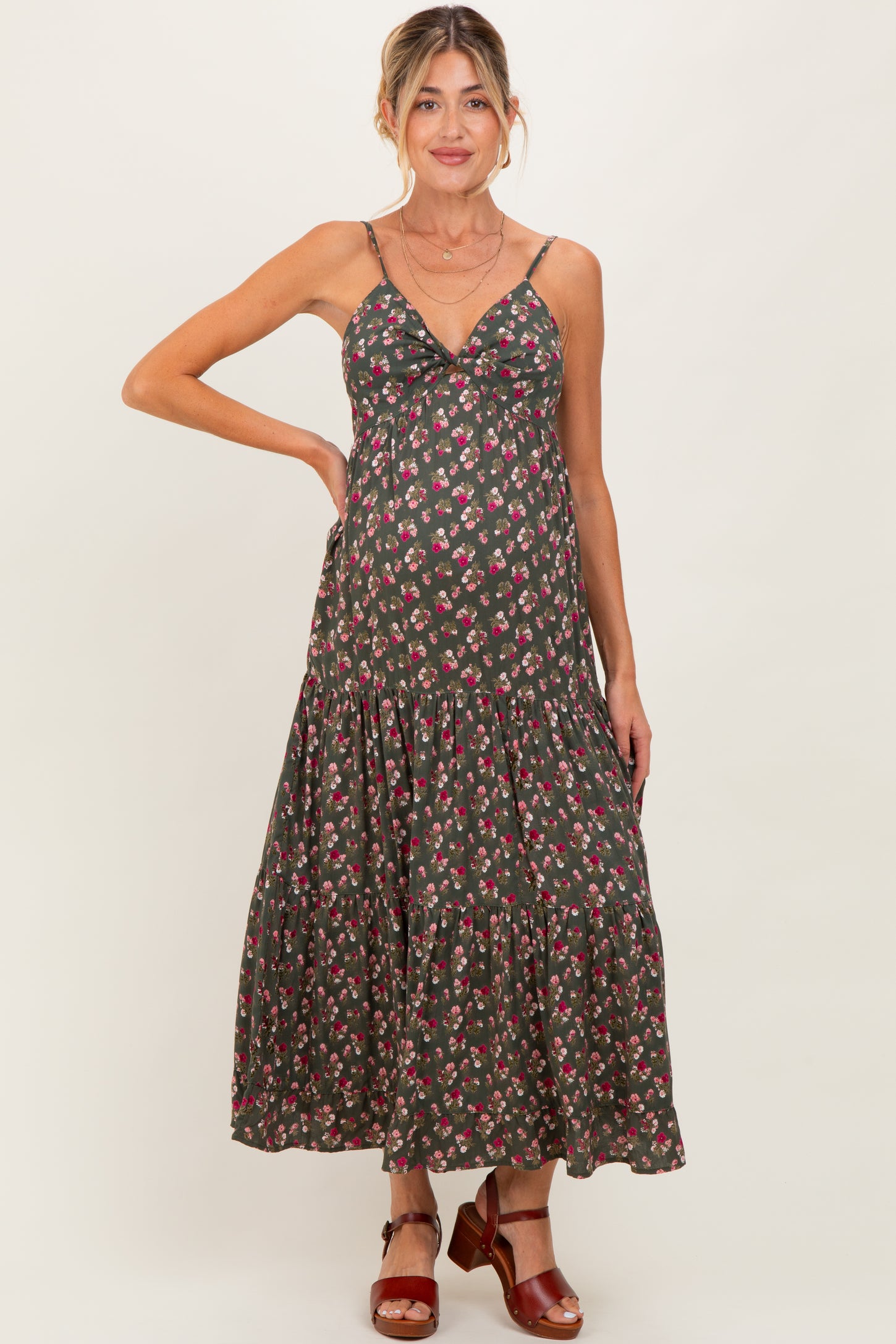 woman wearing a dark floral maternity maxi dress with a ruffled hem and thin straps, showcasing a baby bump