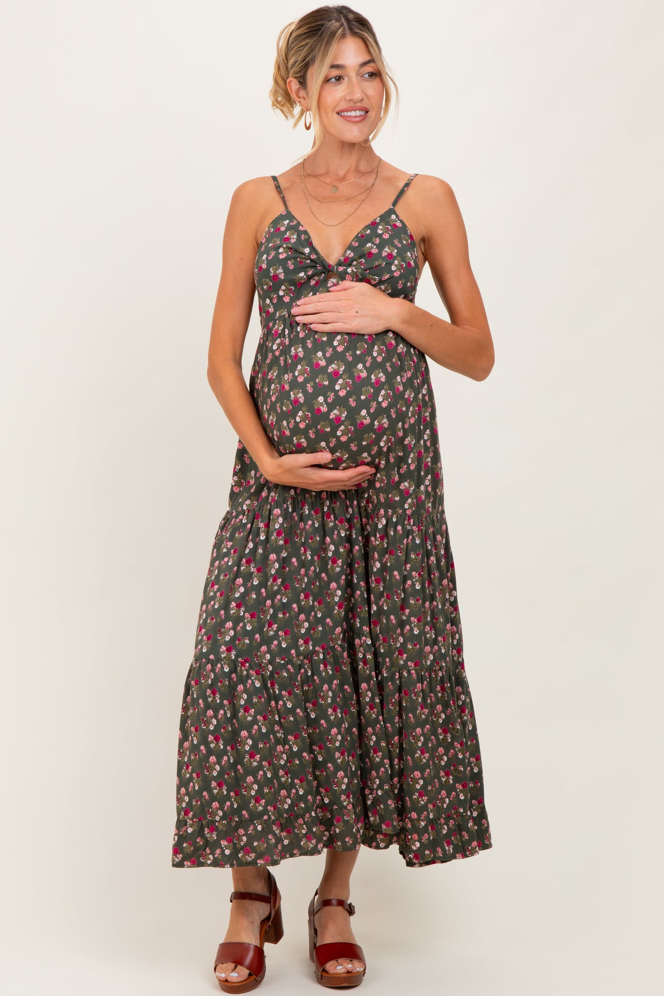 woman wearing a dark floral maternity maxi dress and holding her baby bump