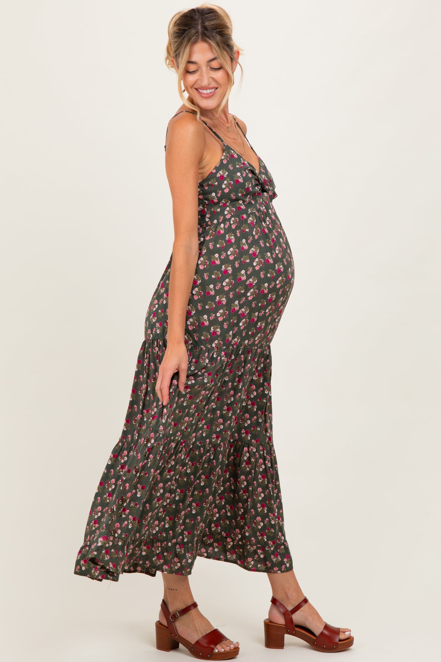 woman wearing a dark floral maternity maxi dress with ruffle details and showing her baby bump