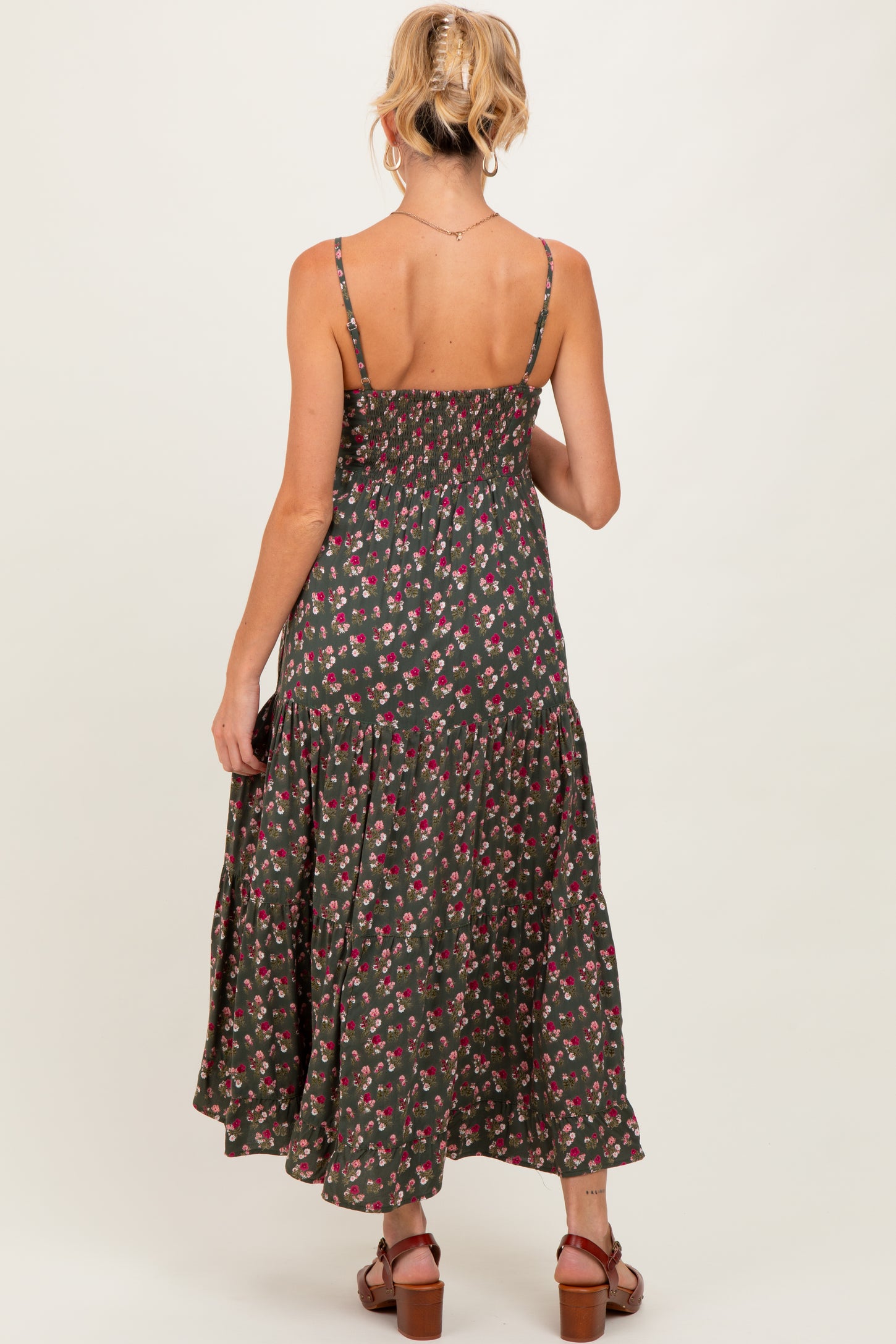 woman wearing a dark green floral maternity maxi dress with smocked back and tiered skirt, view from the back