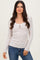 woman wearing a light gray ribbed long sleeve top with lace trim and buttons, paired with blue jeans