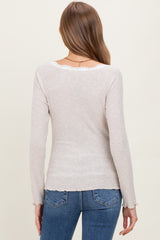 woman wearing a beige ribbed maternity top with long sleeves and a scoop back, styled with blue jeans