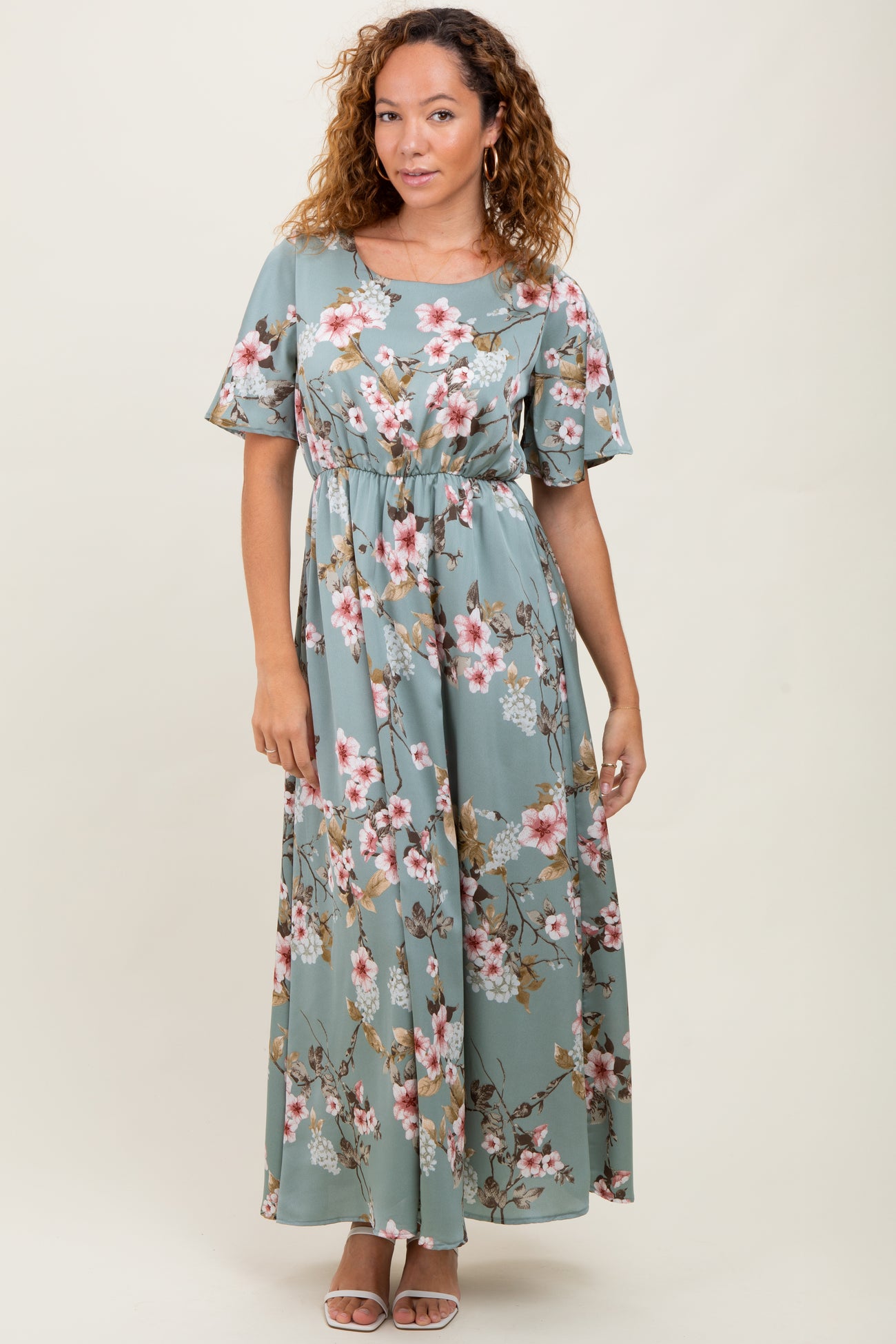 woman wearing a long floral print maxi dress in light teal with short flutter sleeves