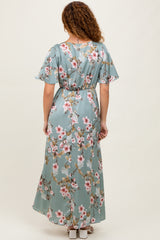 woman wearing a back view of a floral print maxi dress in teal with short flutter sleeves and a cinched waist