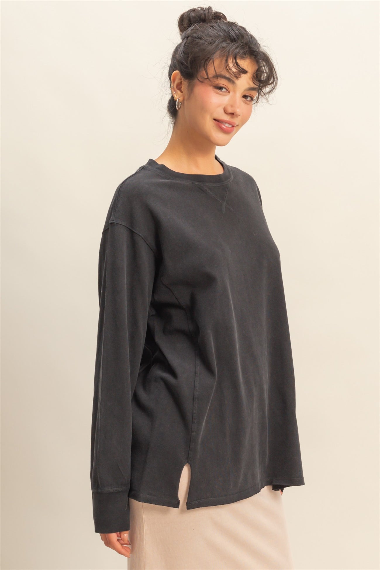 woman wearing a black oversized long sleeve top with a side slit and relaxed fit