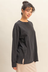woman wearing a black oversized long sleeve top with a side slit and relaxed fit