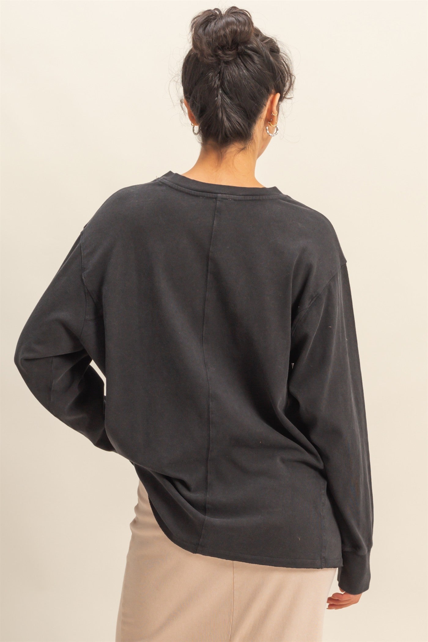 woman wearing a black oversized long sleeve top with a relaxed fit, viewed from the back