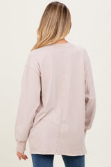 woman wearing a light beige long sleeve maternity top, shown from the back, with relaxed fit and slightly distressed hem