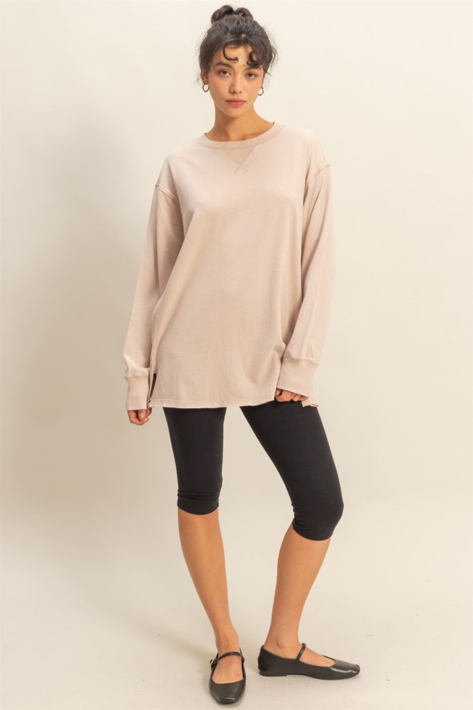 woman wearing a beige oversized long sleeve tee with black leggings and black flats