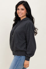 woman wearing a dark gray oversized hoodie with a hood and front pockets, paired with light blue jeans
