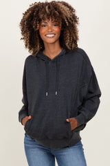woman wearing a dark gray oversized maternity hoodie with a front pocket and hood, styled with light wash jeans