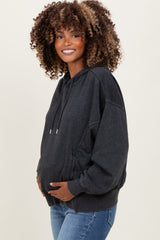 woman wearing a dark gray maternity hoodie with a relaxed fit and holding her baby bump