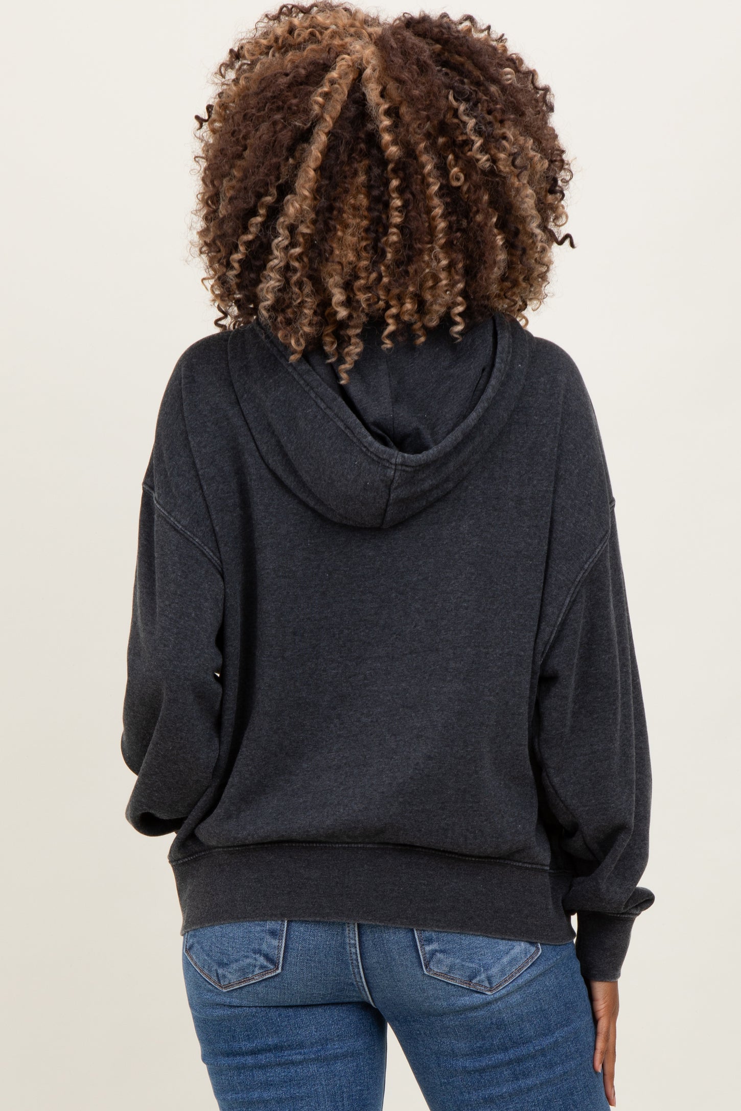 woman wearing a dark gray maternity hoodie with a relaxed fit, showing the back view and paired with blue jeans