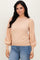 woman wearing a beige sweater with puffed sleeves, paired with blue jeans, smiling at the camera