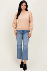 woman wearing a beige ribbed long sleeve top with puffed sleeves and blue cropped jeans with frayed hems