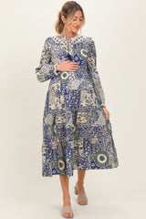woman wearing a blue patterned maternity dress and holding her baby bump