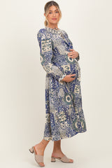 woman wearing a blue and white floral print maternity dress and holding her baby bump