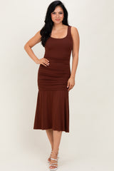 woman wearing a brown sleeveless ruched midi dress with a flared hem and standing pose