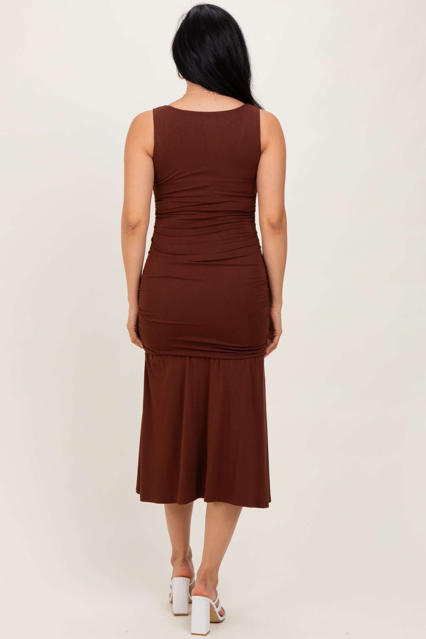 woman wearing a brown sleeveless midi dress with ruching details at the back and a fitted silhouette