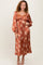 woman wearing an rust floral long sleeve midi dress with puff sleeves and a fitted bodice