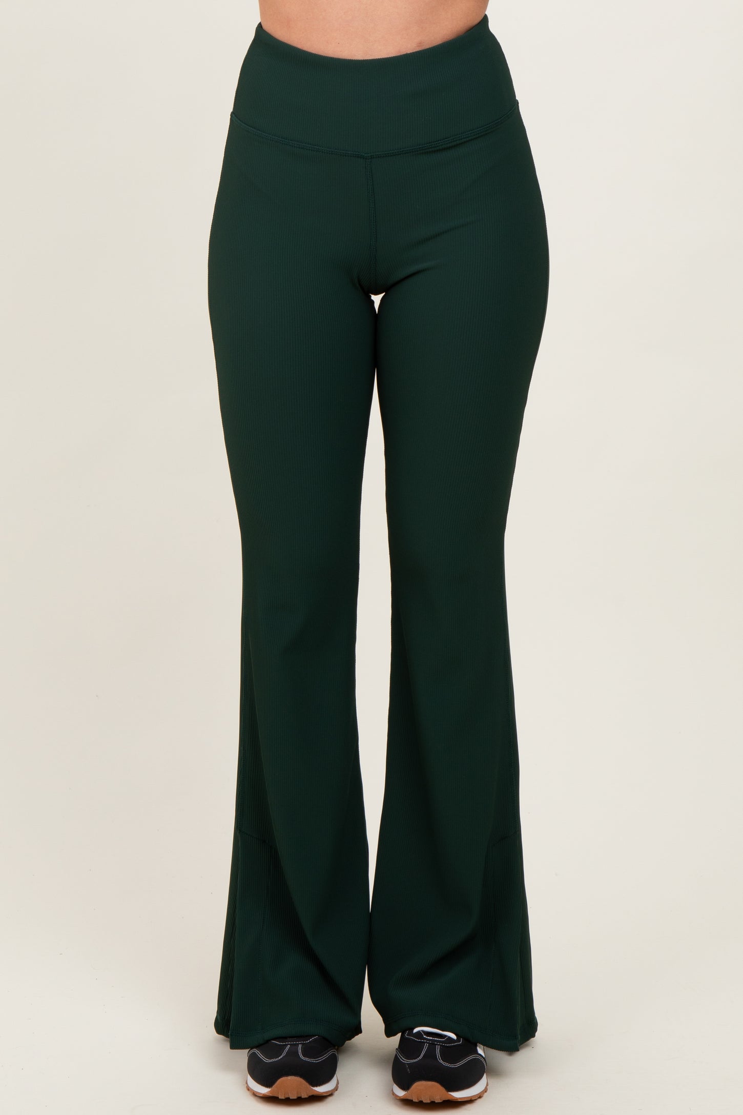 woman wearing green ribbed flared workout pants with a high waist and black sneakers
