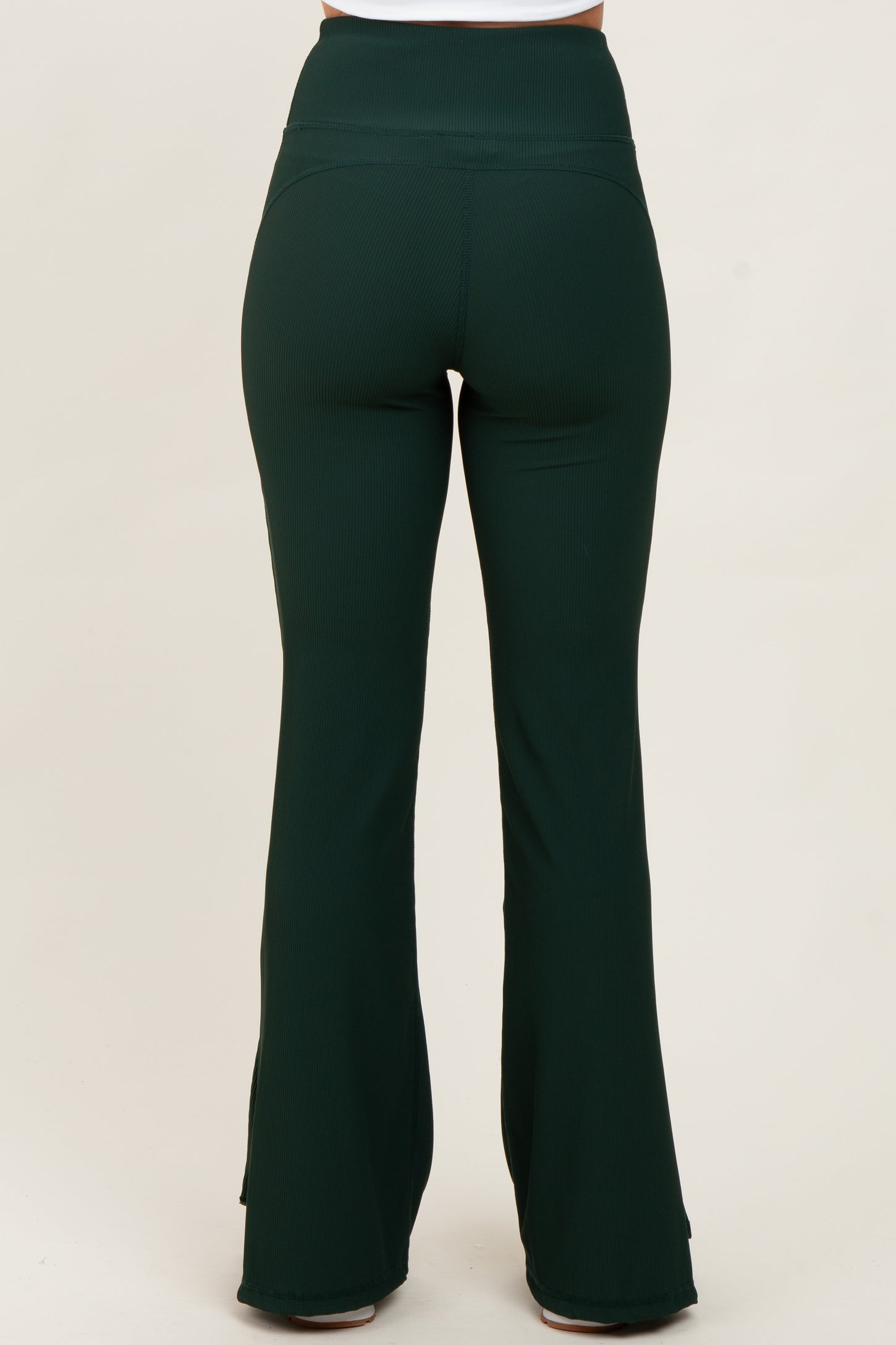 woman wearing dark green ribbed flared pants viewed from the back