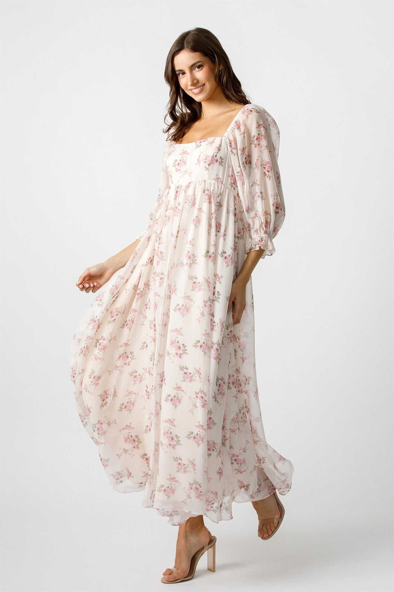 woman wearing a floral print maxi dress with puff sleeves and a square neckline, smiling while posing