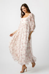 woman wearing a floral print maxi dress with puff sleeves and a square neckline, smiling while posing