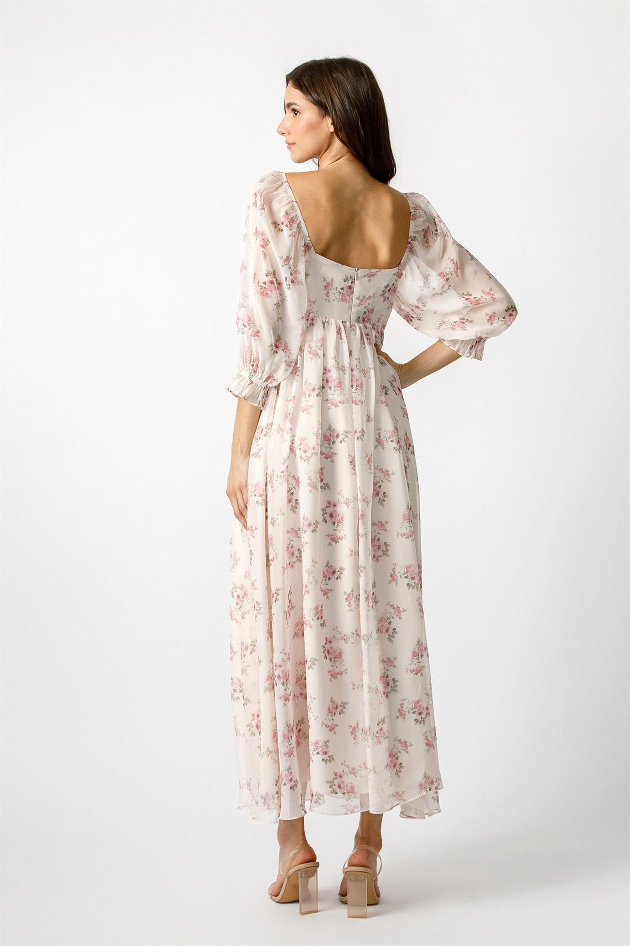 woman wearing a white floral maxi dress with puff sleeves and a square back, standing against a plain background