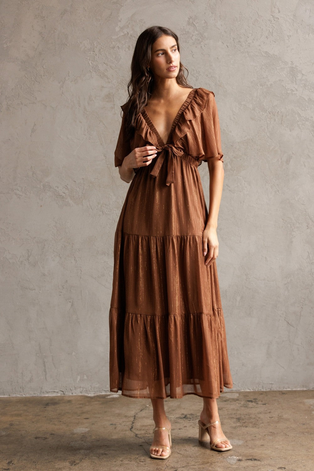 woman wearing a brown tiered maxi dress with ruffle details and a tie front neckline