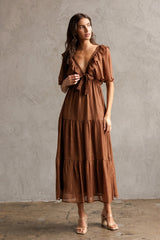woman wearing a brown tiered maxi dress with ruffle details and a tie front neckline