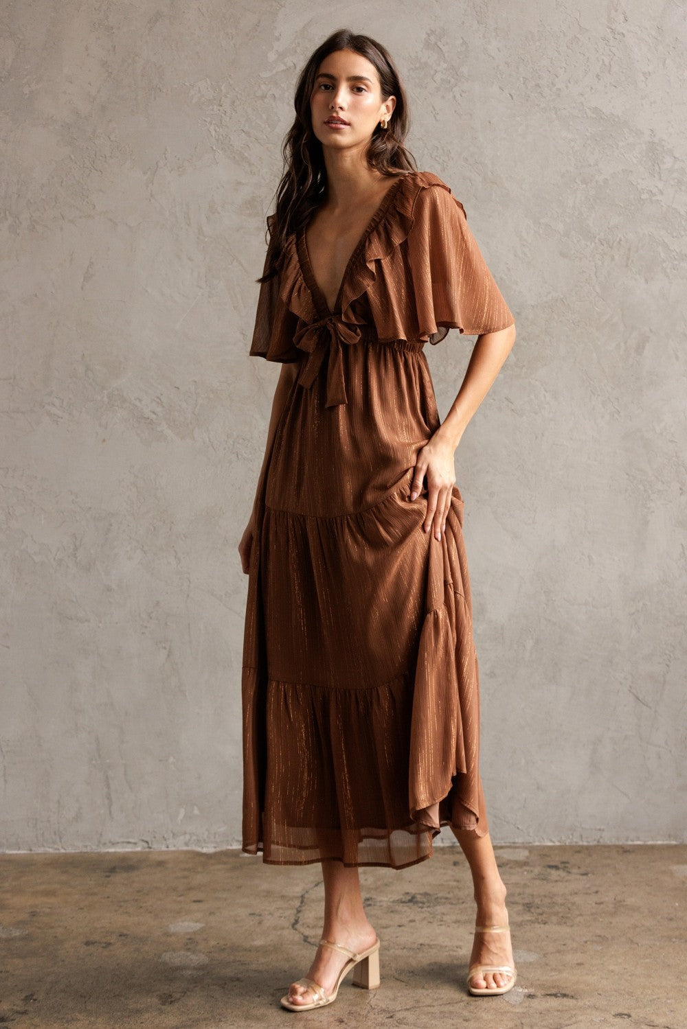 woman wearing a brown tiered maxi dress with ruffle sleeves and a tie front detail