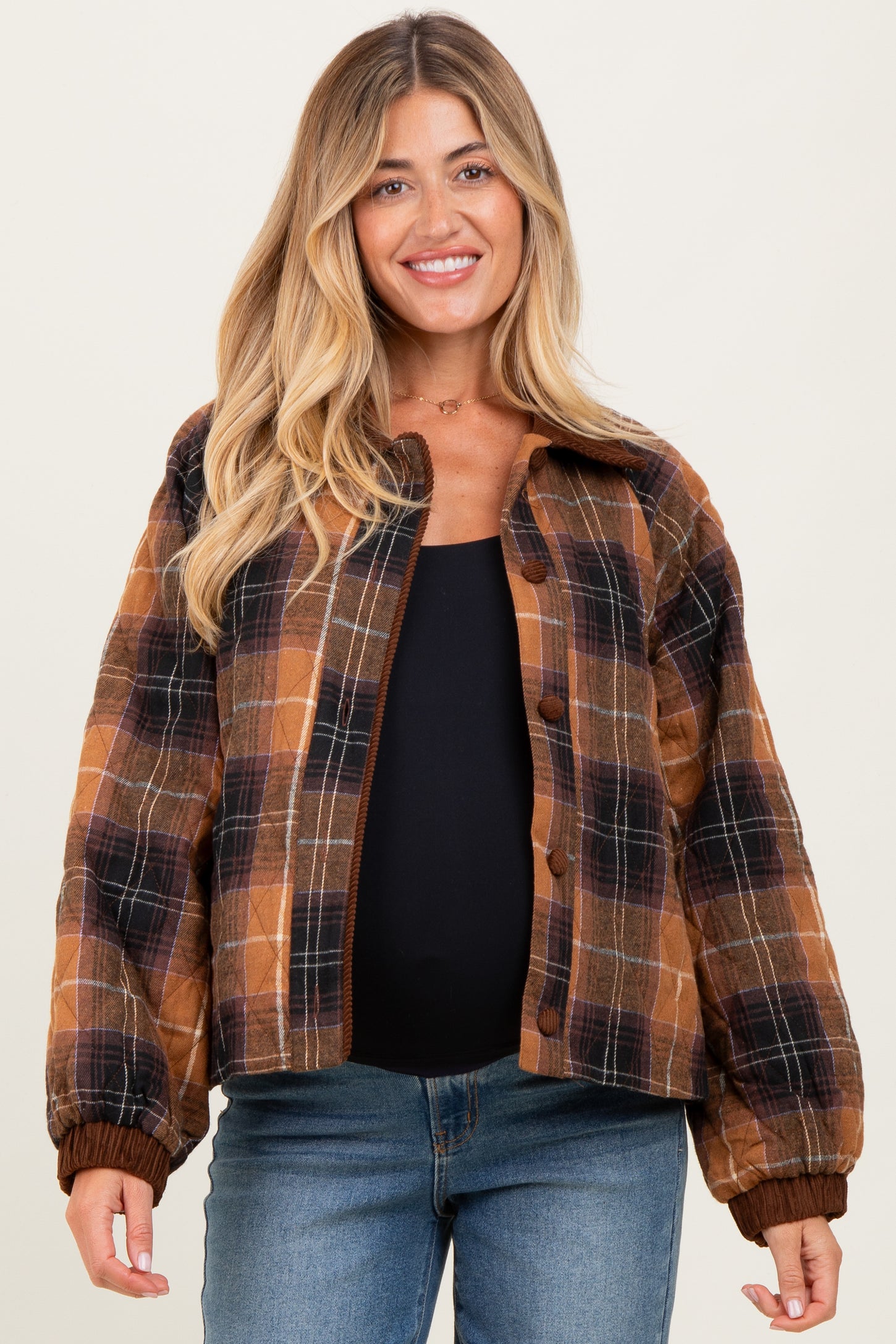 woman wearing a brown plaid maternity jacket with a black top and visible baby bump