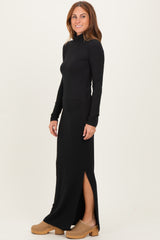 woman wearing a black long sleeve turtleneck dress with a side slit and tan clogs