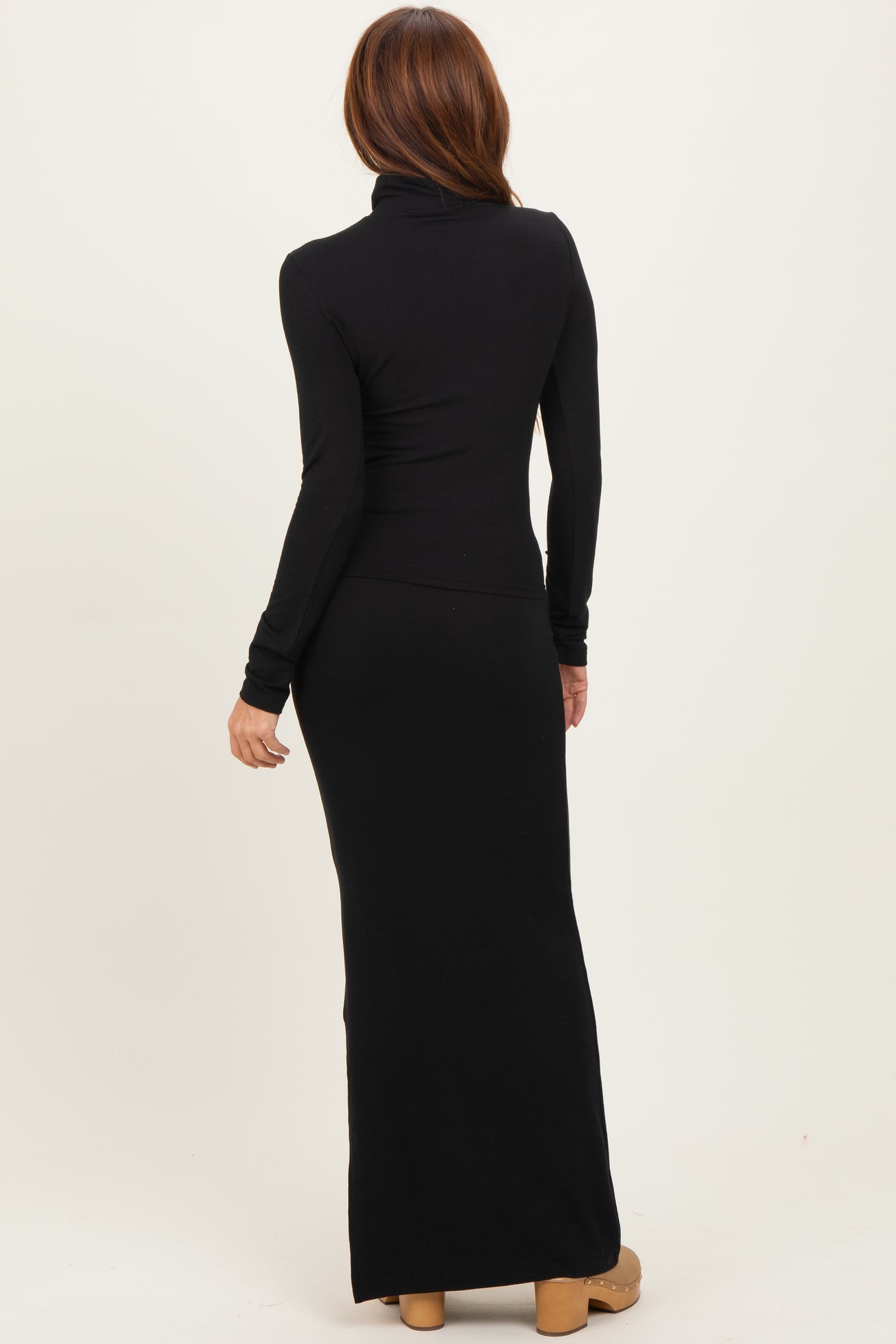 woman wearing a black long sleeve turtleneck maxi dress, shown from the back