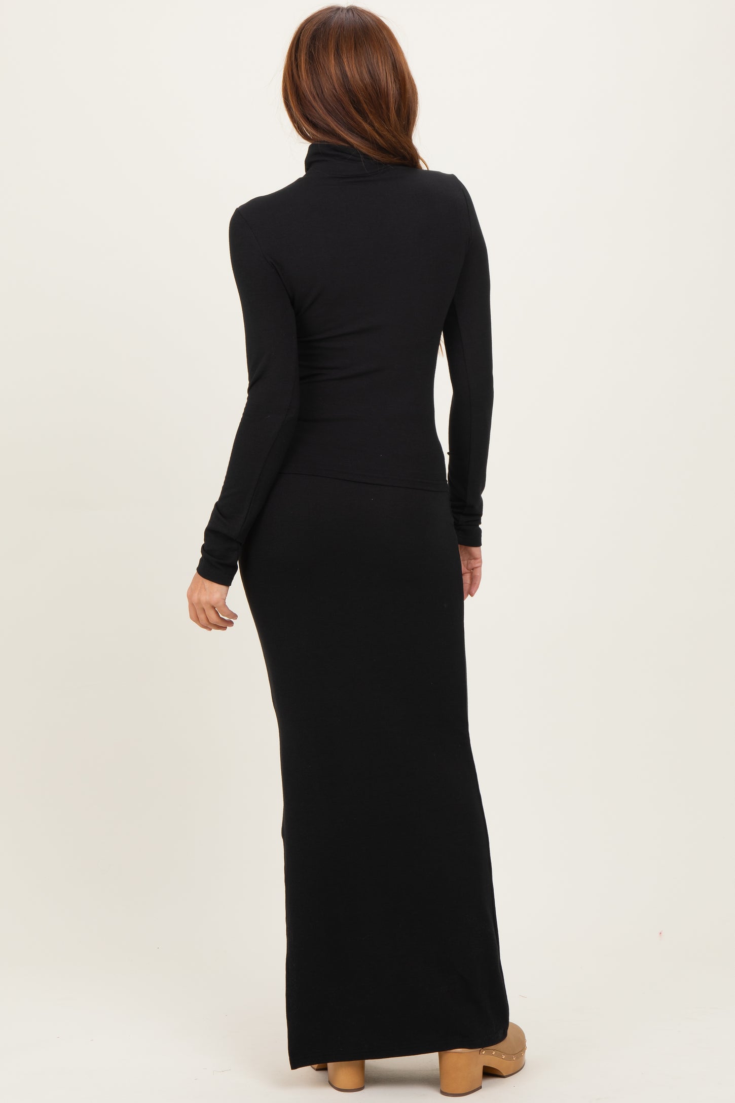 woman wearing a black long sleeve turtleneck maxi dress, shown from the back