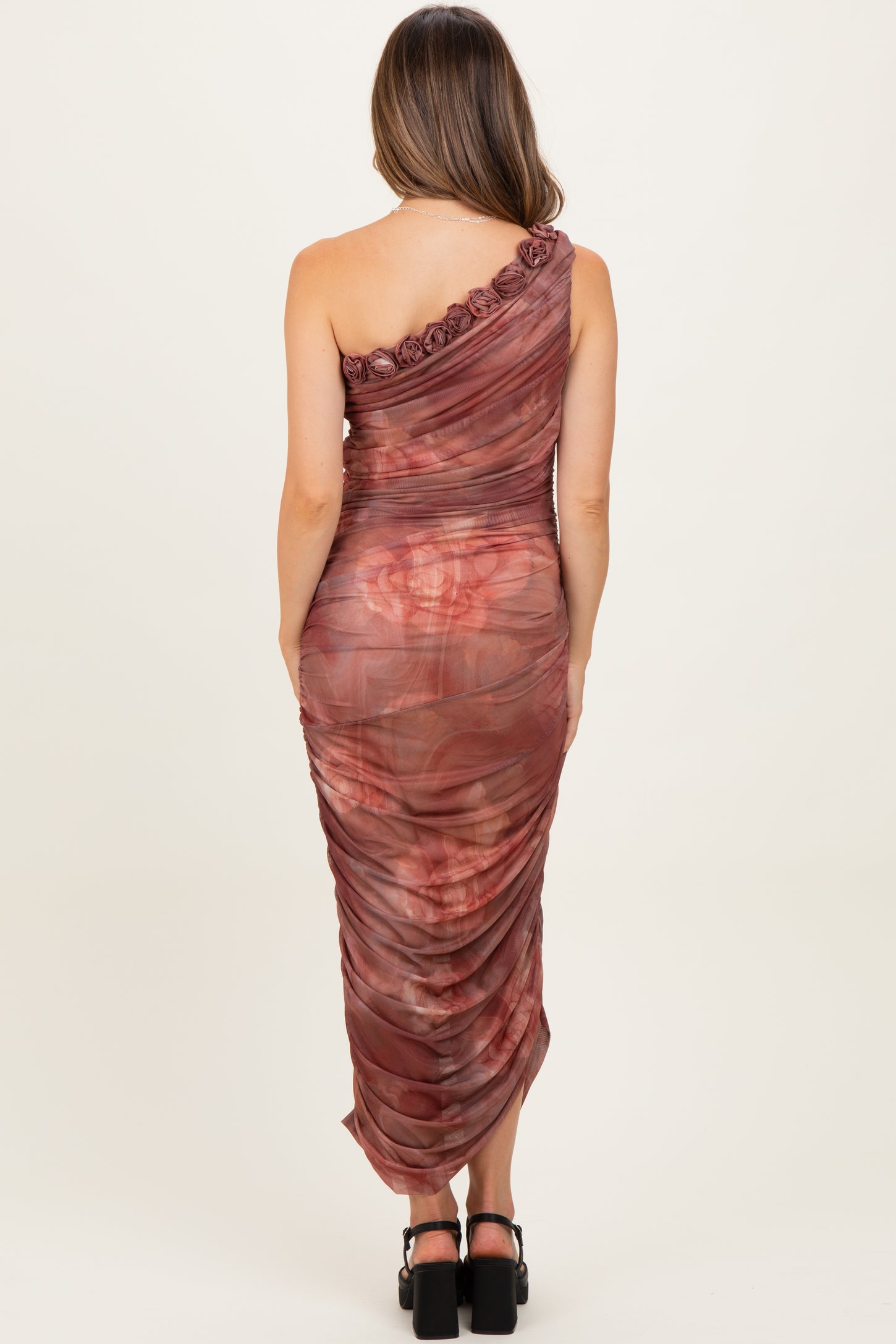 woman wearing a one-shoulder, ruched maternity dress in a burgundy tie-dye pattern