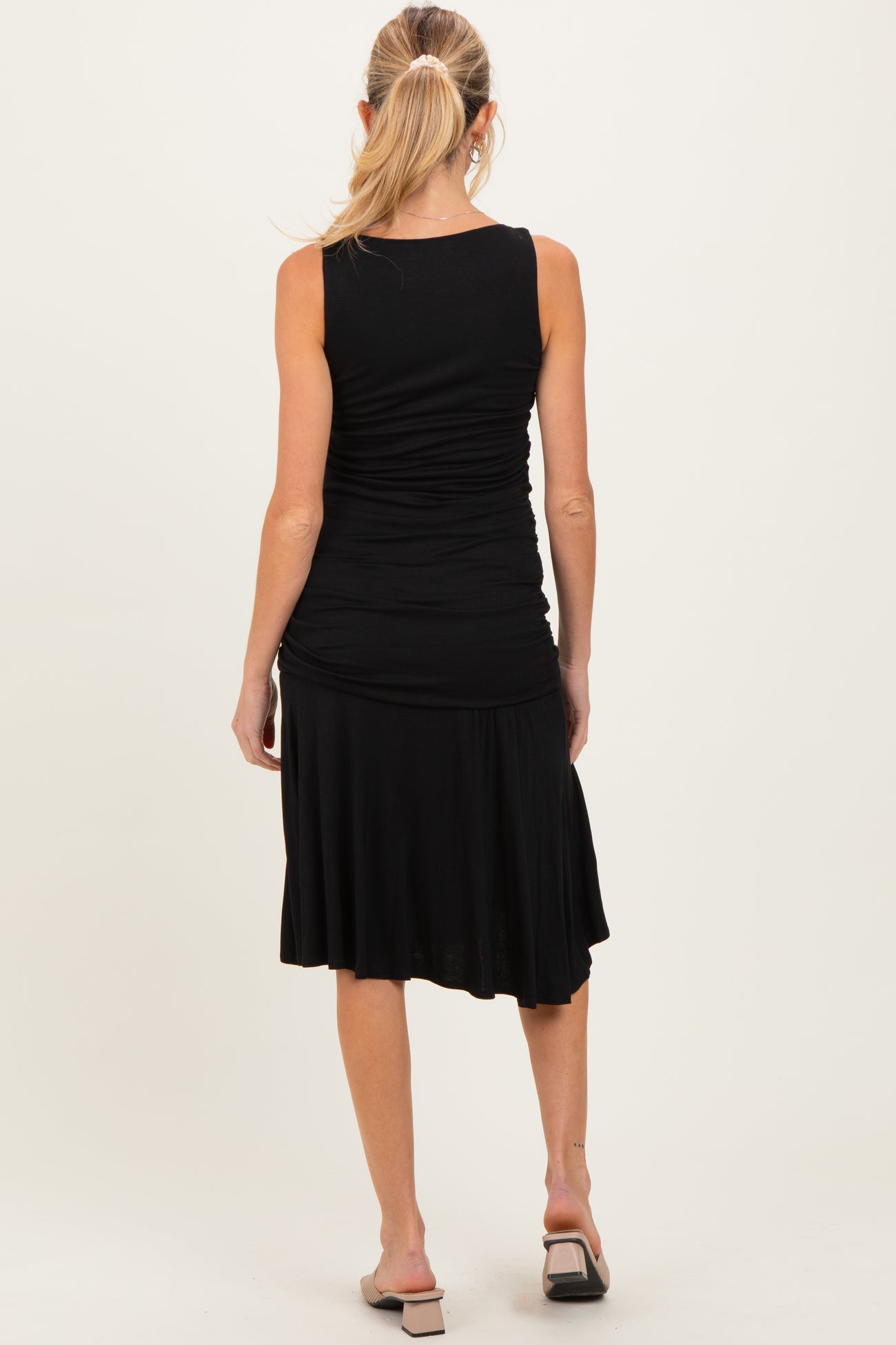woman wearing a black sleeveless maternity dress with a fitted top and flowy skirt, showing a baby bump