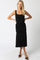 woman wearing a black fitted midi dress with ruching detail and a flared hem, posing with hands on hips
