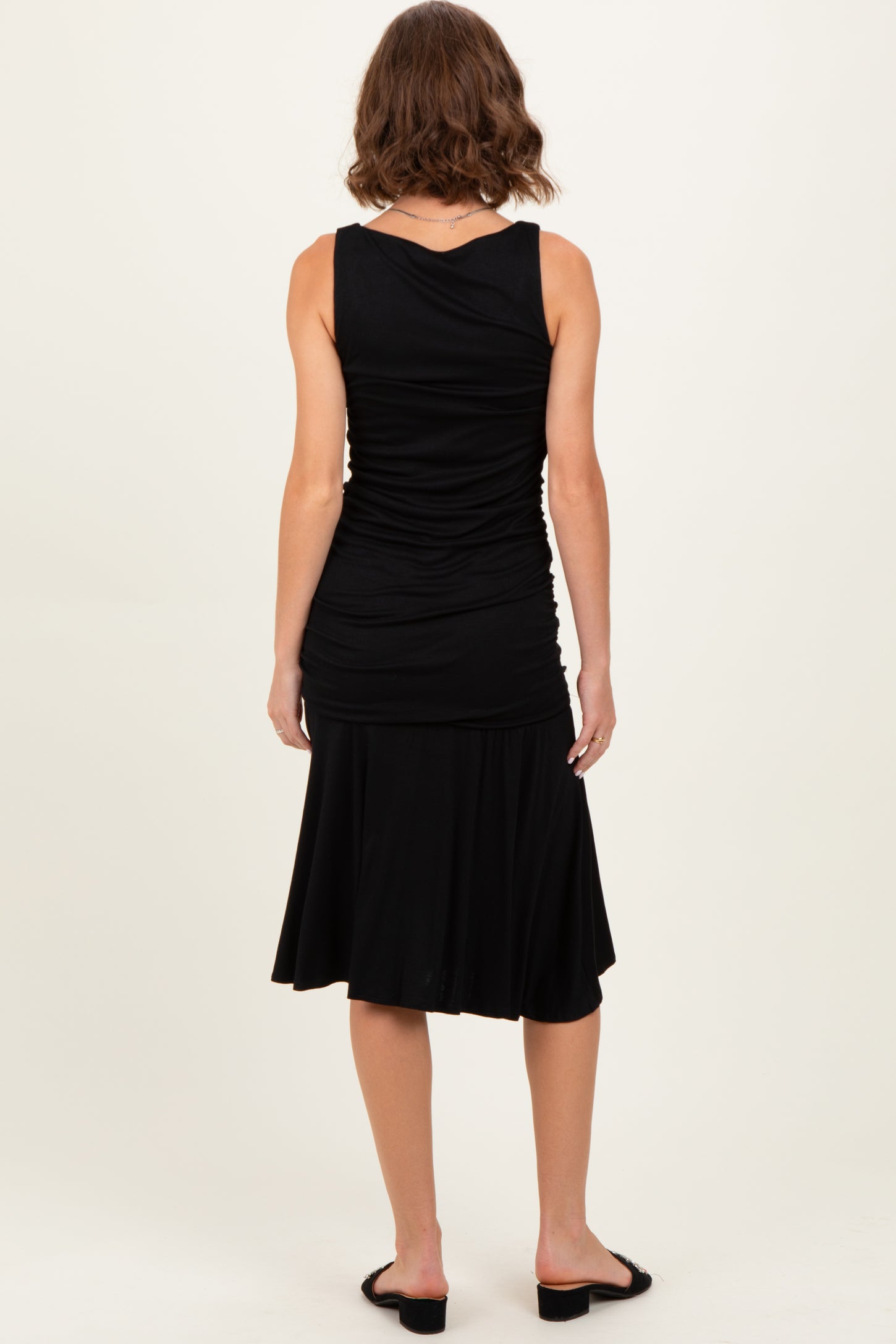 woman wearing a black tank top with gathered details and a flared skirt, viewed from the back