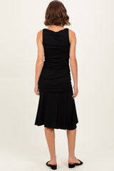woman wearing a black tank top with gathered details and a flared skirt, viewed from the back