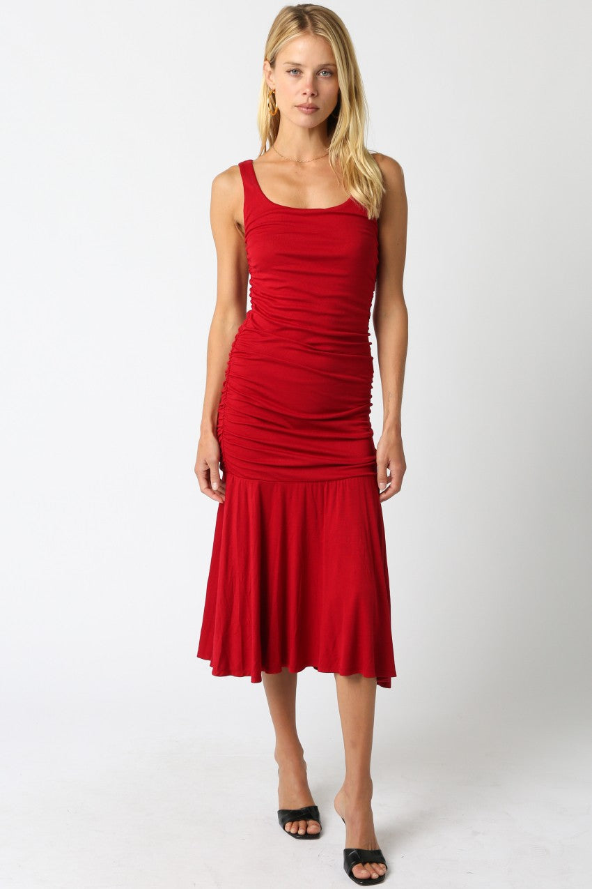woman wearing a red ruched midi dress with a fitted bodice and flared hem