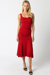 woman wearing a red ruched midi dress with a fitted bodice and flared hem