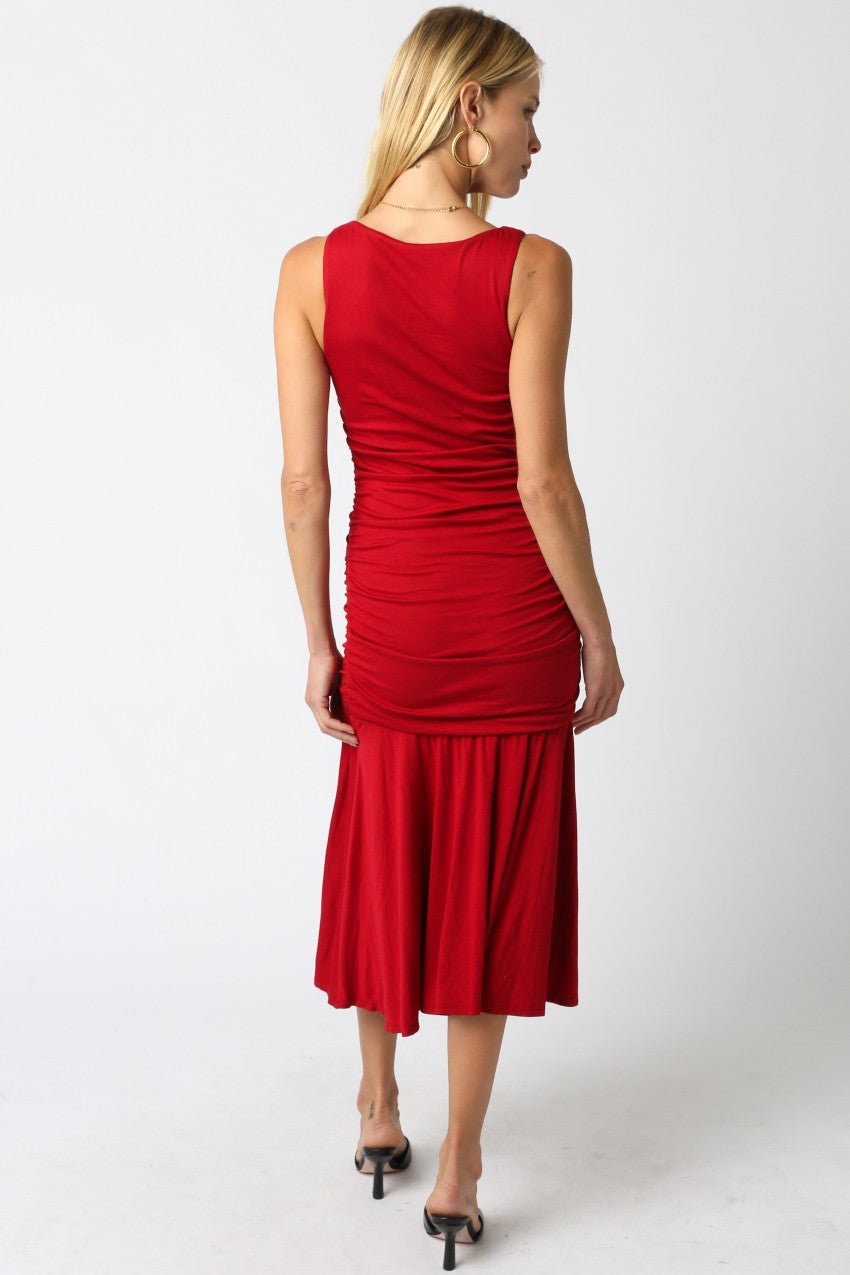 woman wearing a red midi dress with ruched detailing and a flared hem, viewed from the back