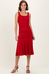 woman wearing a red fitted midi dress with ruching details and a flared hem, paired with strappy heels