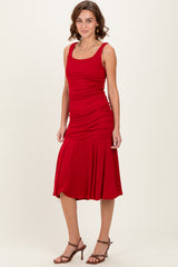 woman wearing a red sleeveless ruched midi dress with a flared hem and strappy heels