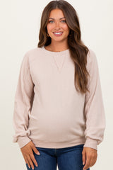 woman wearing a light pink maternity ribbed sweatshirt with a relaxed fit and long sleeves, showing her baby bump