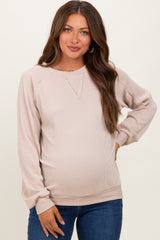 woman wearing a beige ribbed maternity sweatshirt with long sleeves and a baby bump visible